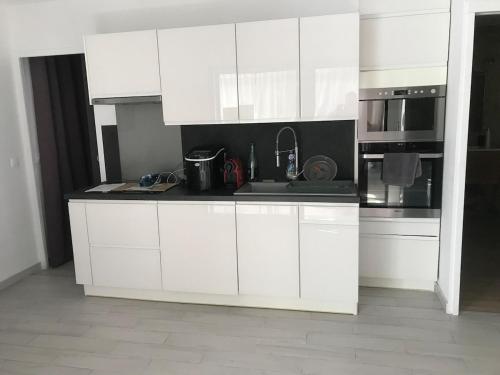 une cuisine blanche avec un évier et un micro-ondes dans l'établissement T2 avec terrasse et accès piscine, à Cassis