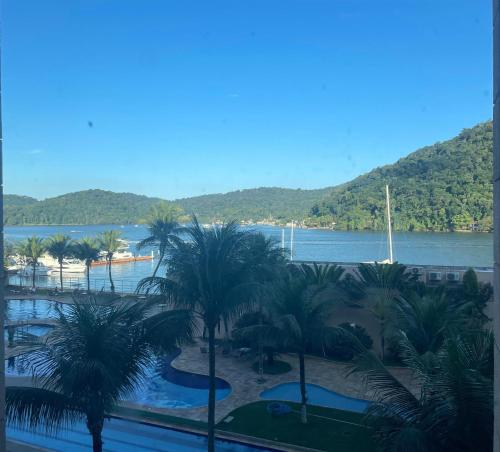 a view of a resort with palm trees and a river at Flat Porto Marina Mont Blanc in Mangaratiba