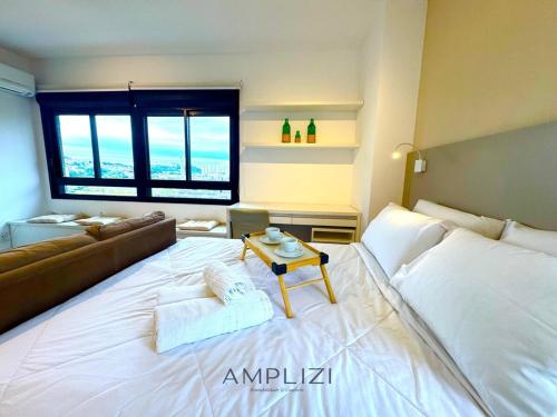 a large white bed in a room with a couch at Nine Amplizi in Porto Alegre