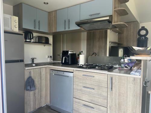 une cuisine avec des armoires blanches et un four à plaques de cuisson dans l'établissement Mobil home familial, au Muy