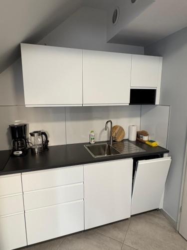 a kitchen with white cabinets and a sink at Apartamenty Na Fali in Kołobrzeg