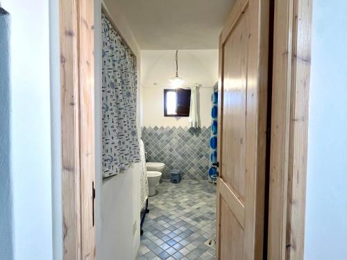 a bathroom with a toilet and a television on a wall at Residence Dammusi Riah in Pantelleria