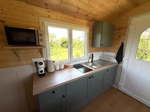 a kitchen with a counter with a sink and a window at La Roulotte de Ville Chérel in Pontorson