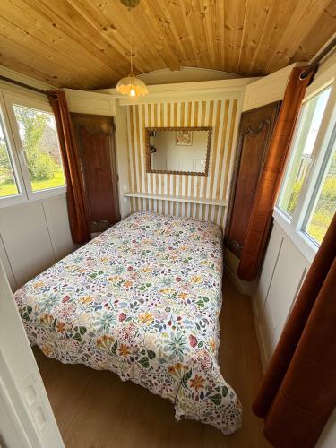 - un lit dans une petite chambre avec 2 fenêtres dans l'établissement La Roulotte de Ville Chérel, à Pontorson