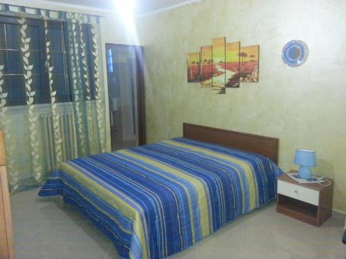 a bedroom with a bed with a blue and yellow striped blanket at B&B La Collina in Collepasso