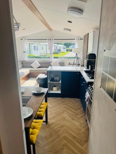 a kitchen with blue cabinets and a table with yellow seats at Haven cleethorpes beach holiday park in Cleethorpes