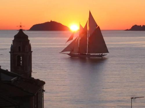 a small sail boat in the water at sunset at La Casa nel Carobio in Ameglia
