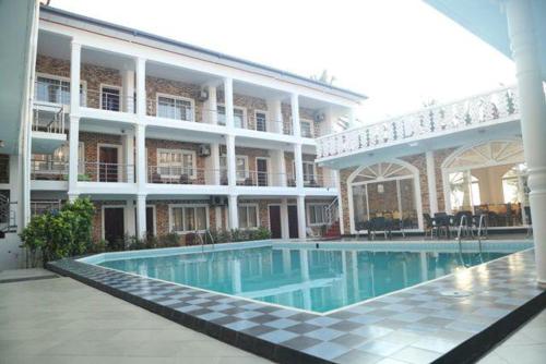 a hotel with a swimming pool in front of a building at Honey beach backpackers in Negombo
