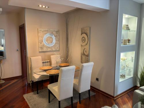 ein Esszimmer mit einem Tisch und weißen Stühlen in der Unterkunft Apartman Centar VV in Kragujevac