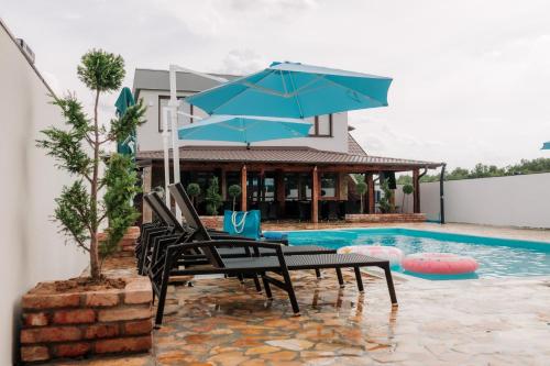 a table with a blue umbrella next to a swimming pool at Villa Cartagena 2 in Brčko
