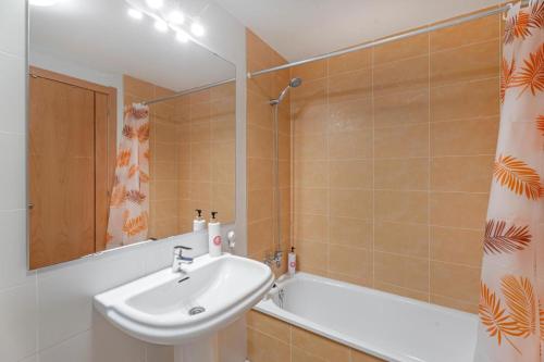 a bathroom with a sink and a tub and a mirror at AleAnto Playa in El Médano