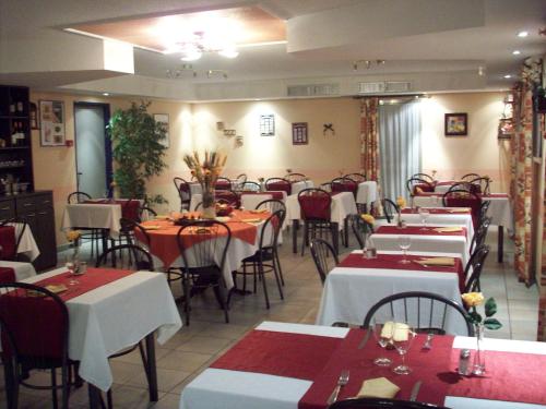a restaurant filled with tables and chairs with red and white tables at Kimotel Epône-Flins in Épône