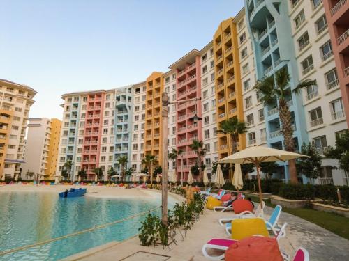 a pool with chairs and umbrellas next to tall buildings at Luxurious Family Chalet - Sia Lagoon, Porto Golf Marina, El Alamien - Lagoon View in El Alamein