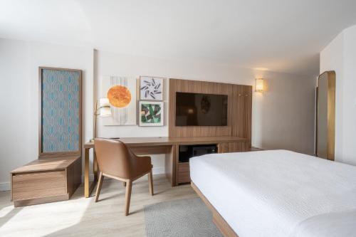 a bedroom with a bed and a desk with a television at Holiday Inn & Suites Winnipeg Downtown by IHG in Winnipeg