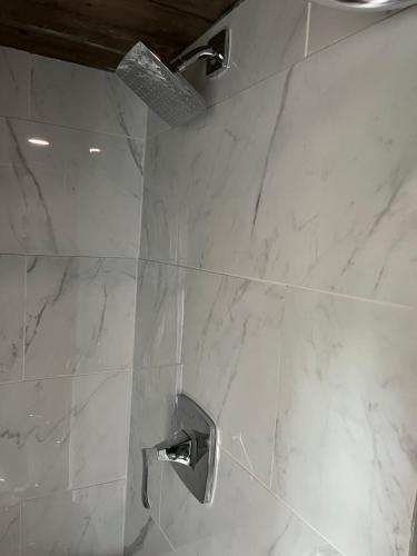 a bathroom with a shower with white marble tiles at Rustic Guesthouse in Sayward