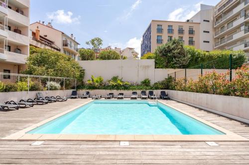 une piscine avec des chaises et un bâtiment dans l'établissement Joséphines, à Cannes