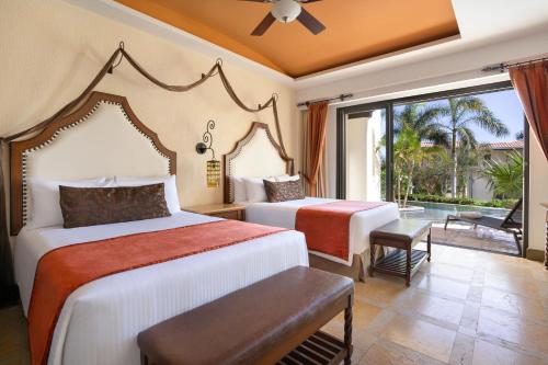 a hotel room with two beds and a balcony at Secrets Puerto Los Cabos Golf & Spa18+ in San José del Cabo