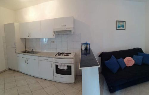 a kitchen with a stove top oven next to a couch at Relax Apartments Grazia in Funtana