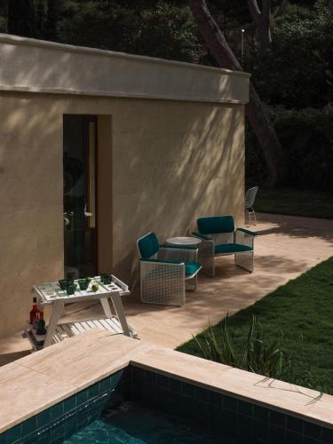 un patio avec une table et des chaises à côté d'une piscine dans l'établissement Maison Californienne avec piscine proche de la mer, à Marseille