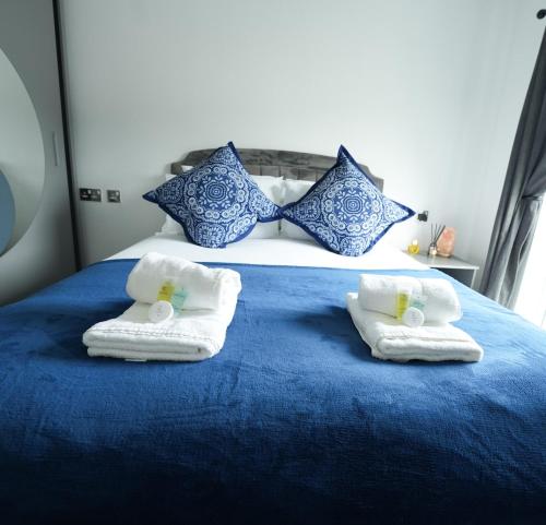a blue bed with towels and pillows on it at Stylish 1-Bedroom Apartment sleeps 4 in Swansea
