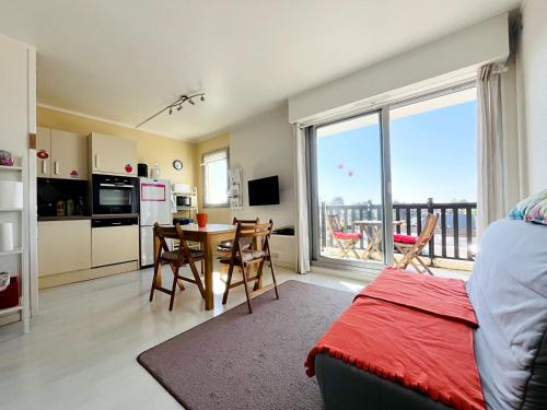 Il comprend un salon avec une table et une cuisine avec un balcon. dans l'établissement T2 Logement entier, balcon, piscine, tennis et accès direct à la plage!, à Cabourg