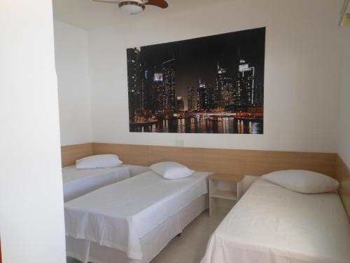 two beds in a room with a picture of a city at Pousada Dubai in Taubaté