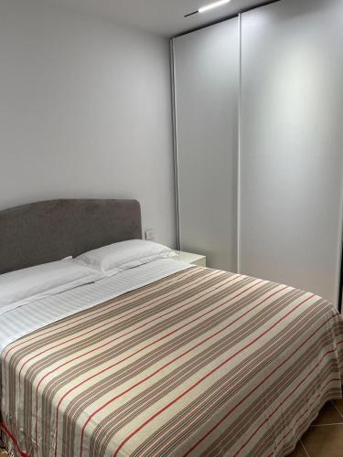 a bedroom with a bed with a striped blanket at Glory's Apartments Sarande in Sarandë