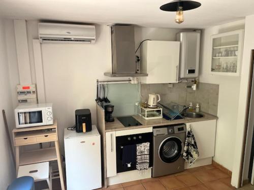 une cuisine avec un lave-linge et un micro-ondes dans l'établissement Vasandries, à Ollioules