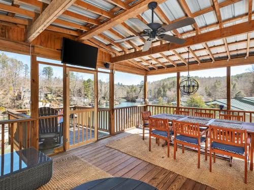 a screened porch with a table and chairs and a television at Lakefront House In A Quiet Cove - Kayaks Available in Lake Lure