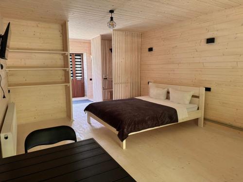 a bedroom with a bed in a room with wooden walls at Садиба у Курила з сауною та чаном на дровах in Shepot