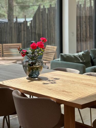 a vase with red flowers sitting on a wooden table at Willa Horyzont Borsk in Borsk