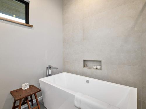 a white bath tub in a bathroom with a stool at Luxe 5BR with Home Theater, Pool Table and Firepit in Stoney Knob