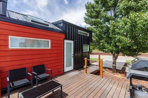 a red and black house with two chairs on a deck at Hot Tub & BBQ Deck, Tiny Home Near Zion National Park in Apple Valley