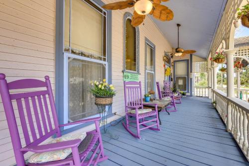 a row of purple rocking chairs on a porch at Grand Gables Home 1 Block to St Johns River! in Palatka