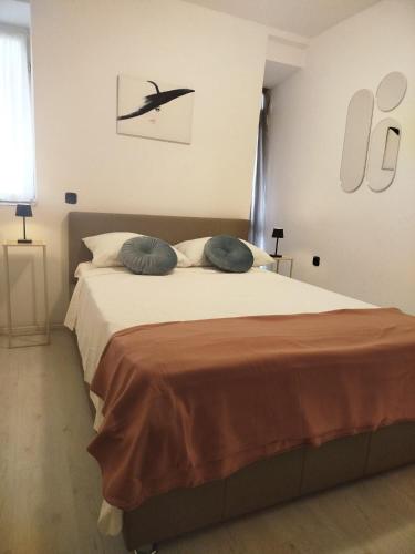 a bedroom with a large bed with two blue pillows at Apartments Rose in Zaton