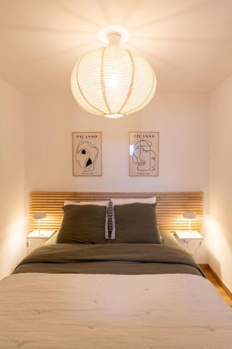 une chambre avec un grand lit et un lustre dans l'établissement Charmant duplex T4 à Loudenvielle à 50m du skyvall, à Loudenvielle