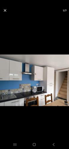 une cuisine avec des armoires blanches et une table et des chaises dans l'établissement Gîte du bonheur, à Éperlecques