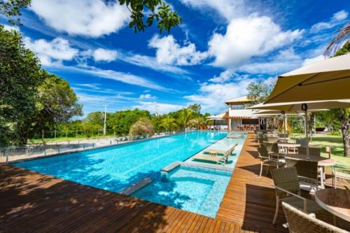 プライア・ド・フォルテにあるCasa em Praia do Forte Refúgio Luxo e Naturezaの椅子とパラソルのあるリゾートのプール