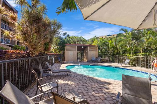 a swimming pool with chairs and an umbrella at MV2123 Serene Hawaiian Beachside Bliss in Kihei