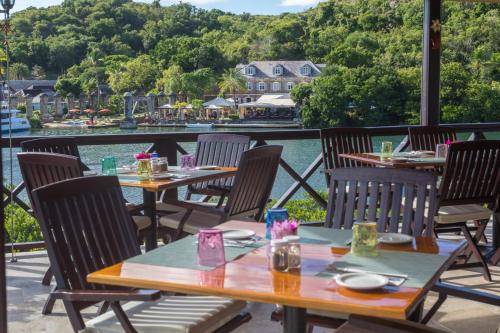 a patio with tables and chairs with a view of the water at Gunpowder House & Suites in English Harbour Town