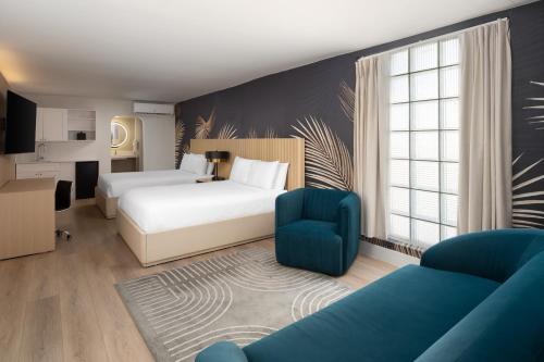 a hotel room with two beds and a blue chair at The Harrison Downtown Hollywood in Hollywood