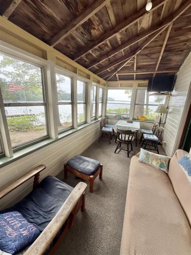 a room with a couch and a table and windows at PARADISE POINT LIMIT 10 cottage in Casco