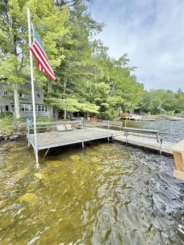 a dock with an american flag in the water at PARADISE POINT LIMIT 10 cottage in Casco