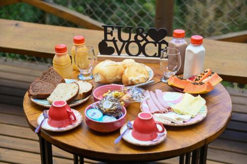 a wooden table with plates of food and bottles of milk at Recanto Lira 2 in Monte Verde