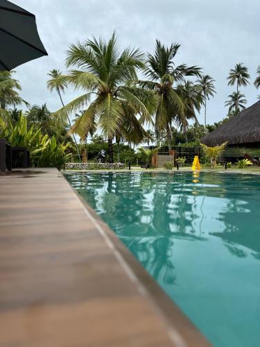 a swimming pool with palm trees in the background at Villa Naluri - Casa Yodo - Apartamento 1 quarto em Japaratinga in Japaratinga