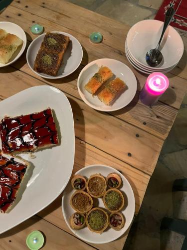 a wooden table topped with plates of food and desserts at Hartna zaman in Taiyiba