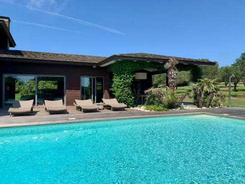 une piscine avec des chaises et une maison dans l'établissement Villa Lavezzi, à Bonifacio