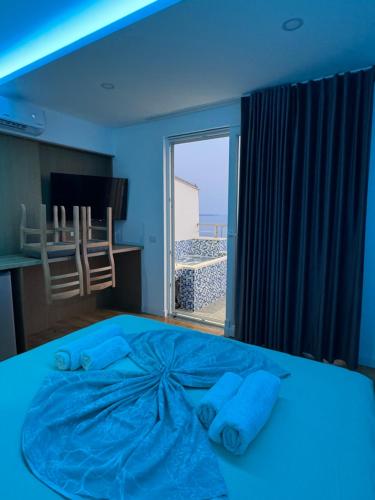a blue bedroom with a large bed with a window at Suite Rana Hedhun in Shëngjin