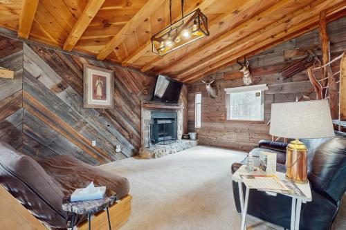 a living room with a fireplace in a log cabin at Bigfoot Lodge in Angel Fire