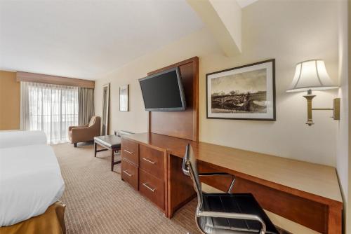 a hotel room with a bed and a desk with a television at Best Western Alamo Suites in San Antonio